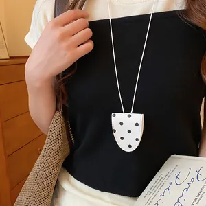 Detail van de retro witte polkadot brillenhouder ketting gedragen als modeaccessoire