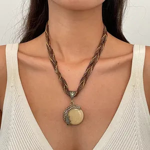 Detailweergave van een vintage boho halsketting met hars hanger gedragen door een model