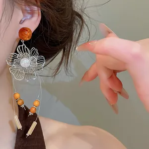 Detailed close-up of vintage resin hollow flower tassel earrings with pearl accents