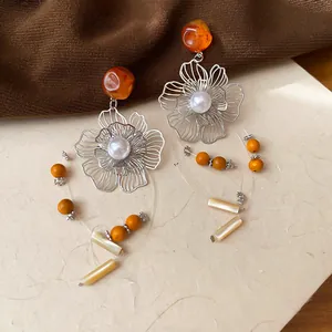 Detailed macro view of vintage hollow flower earrings with tassels and orange resin beads
