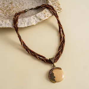 Detailopname van vintage gevlochten halsketting met gemarmerde hars hanger en strass-steentjes