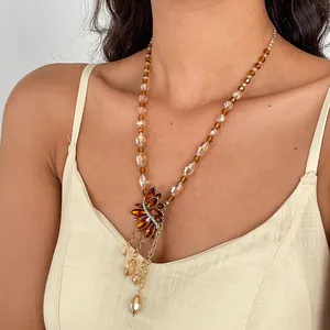 Detailweergave van amberkleurige glasparelketting met strass-blad kwastjeshanger