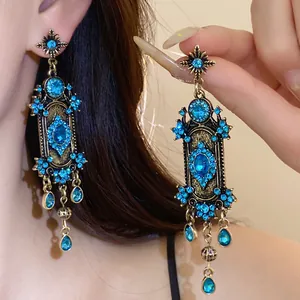Gros plan détaillé de boucles d'oreilles bohèmes vintage avec strass bleu brillant portées