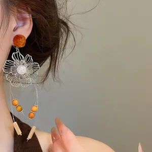 Close-up of elegant resin hollow flower earrings with pearl and beaded tassels.