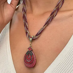Detailopname van een vintage halsketting met een druppelvormige hanger en rode strassteentjes