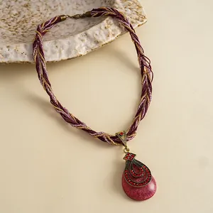 Detail van retro waterdruppel hanger ketting met rode strass en gevlochten koord