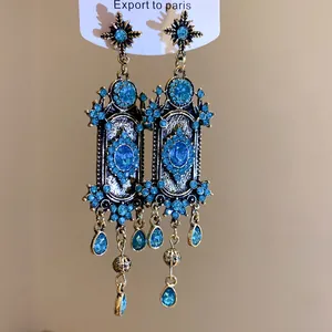 Détail rapproché de boucles d'oreilles bohèmes vintage avec cristaux bleus et strass.