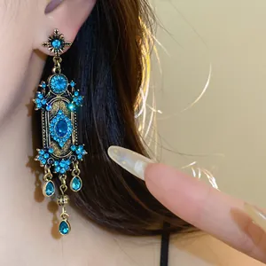 Détail de boucles d'oreilles bohèmes rétro avec strass bleus et glands pendants.