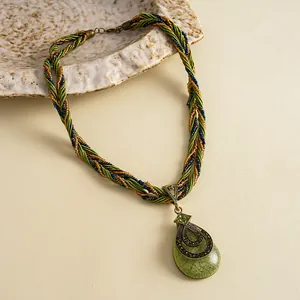 Detail van een vintage ketting met groene druppelhanger en een mooie gevlochten band