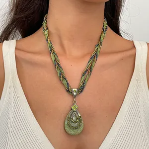 Detailopname van vintage druppelketting met groene hars hanger en kralenkoord