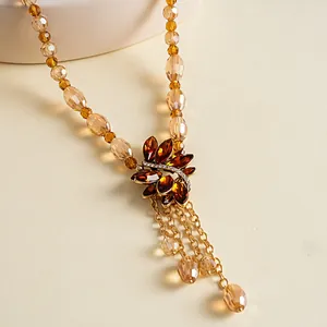 Detailweergave van elegante ketting met amberkleurige glazen bladeren en schitterende strass-accenten