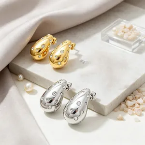 Detailed view of elegant gold and silver teardrop stud earrings with sparkling rhinestones