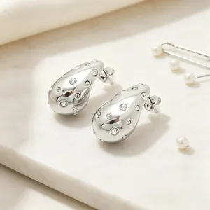 Close-up of polished stainless steel teardrop earrings with sparkling rhinestones