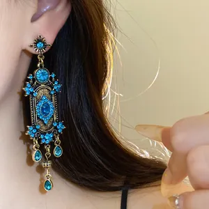 Gros plan de boucles d'oreilles bohèmes vintage avec strass bleus et glands en forme de goutte