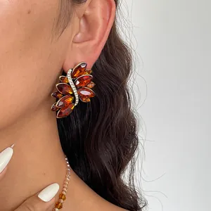Close-up van amberkleurige blad oorbellen en kralenketting op een elegant model