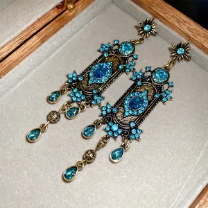 Gros plan de boucles d'oreilles bohèmes vintage avec strass bleus dans une boîte en bois