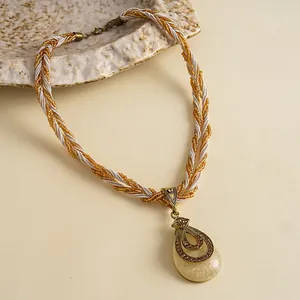 Gedetailleerde close-up van een vintage druppelhanger met hars en gevlochten ketting