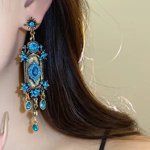 Gros plan détaillé de boucles d'oreilles bohèmes vintage avec strass bleus et glands élégants.