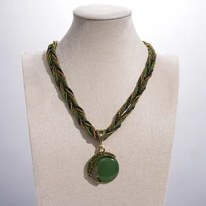 Detailweergave van een vintage ketting met groene hars hanger op een mannequin.