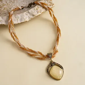 Detailopname van een vintage gevlochten ketting met een hanger van hars en fonkelende strass.