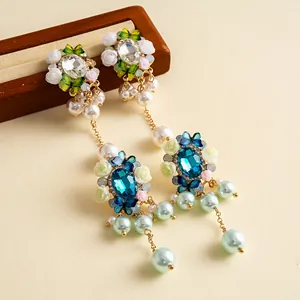 Primo piano di orecchini a fiori con cristalli blu e nappe di eleganti perle.
