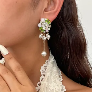 Primo piano di orecchini a fiore in cristallo con farfalle e nappe di perle su modella