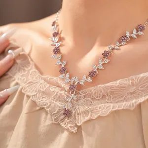 Close-up of elegant floral necklace with purple crystals on a model wearing lace.