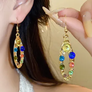 Vue détaillée d'élégantes boucles d'oreilles ovales dorées avec strass colorés