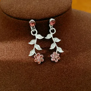 Close-up detail of palace style silver earrings with pink flower and leaf rhinestone motifs
