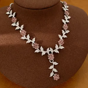Close-up of elegant silver-toned floral necklace with pink and clear crystals.