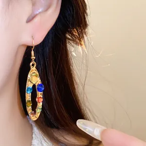Vue détaillée de boucles d'oreilles ovales dorées avec perles multicolores facettées