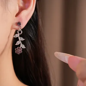 Close-up of palace style purple rhinestone leaf and flower dangle earrings on ear.
