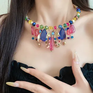 Détail d'un collier de perles en acrylique coloré avec des pendentifs géométriques sur modèle
