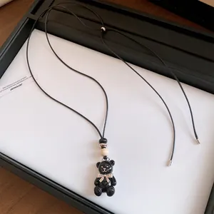 Primo piano del pendente orso in resina nera con perla in legno e fiocco.