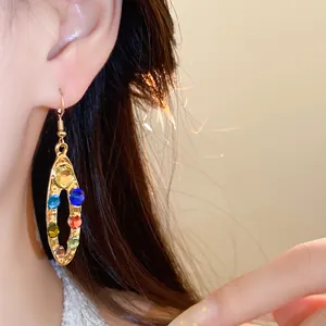 Gros plan détaillé d'une boucle d'oreille ovale dorée ornée de strass colorés vibrants