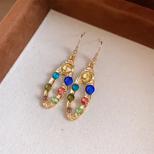 Gros plan de boucles d'oreilles ovales géométriques avec strass colorés et finition dorée