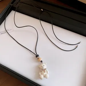 Dettaglio ravvicinato di collana con ciondolo orso in resina bianca e fiocco