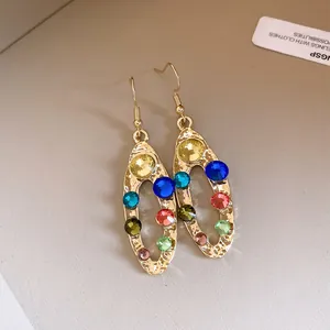 Vue détaillée de boucles d'oreilles pendantes ovales en strass colorés avec fini doré