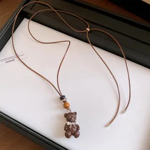 Dettaglio di una collana con ciondolo a forma di orso in resina marrone e cordino