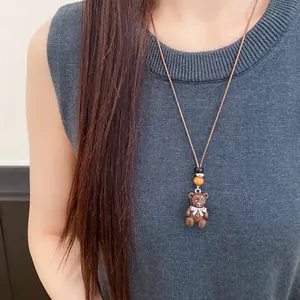 Dettaglio di una collana con orsetto in resina marrone e cordino in pelle su modella.