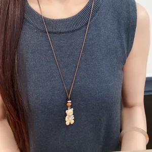 Primo piano della collana con ciondolo a forma di orsetto in resina con un fiocco