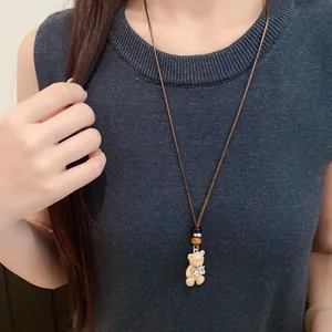 Dettaglio della collana con ciondolo a orsetto, cordino in pelle e fiocco decorativo