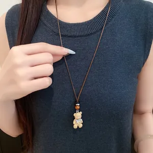 Dettaglio collana orsetto in resina con fiocco argento e perlina in legno su cordino marrone