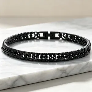 Dettaglio di bracciale cubano nero in acciaio al titanio con doppia trama e chiusura a gioiello.
