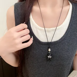 Primo piano di una dolce collana con ciondolo a forma di orso nero in resina e perline di legno