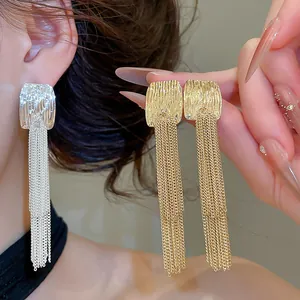 Detailansicht eleganter Quastenohrringe in Gold und Silber mit strukturierter Metalloberfläche.
