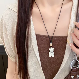 Primo piano di una collana con orsetto in resina, perla in legno e cordino in pelle