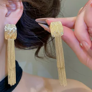 Nahaufnahme von goldenen gefalteten Metallsteckern mit eleganten Kettchen-Quasten