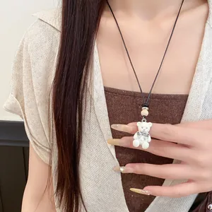 Dettaglio ravvicinato di una collana con ciondolo a forma di orso in resina bianca e fiocco