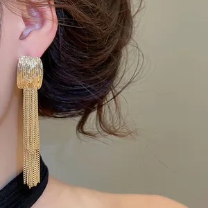 Detailansicht eleganter goldener Ohrstecker mit langen mehrlagigen Kettenquasten.